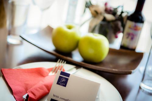 a plate with two green apples on a table with a menu at Hotel Palace Marina Dinevi in Sveti Vlas