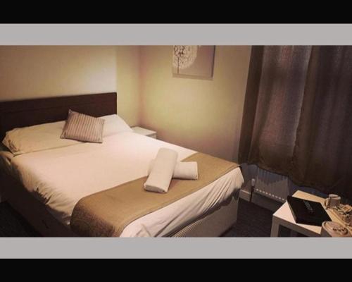 a hotel room with a bed with a towel on it at The R Inn Hotel in Desborough