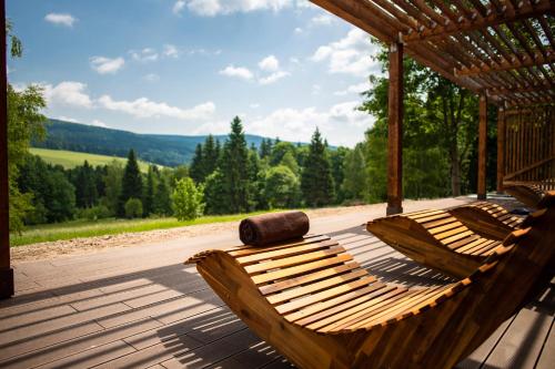two wooden hammocks sitting on a deck with a view of the mountains at Amenity Hotel & Resort Orlické hory in Deštné v Orlických horách