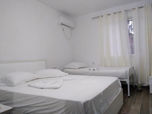 two beds in a white room with a window at Condo Rooms in Sarandë