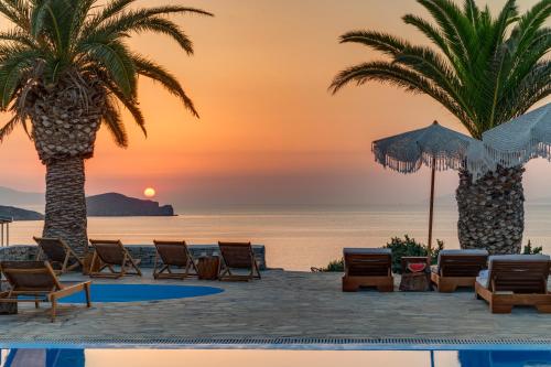 a view of a beach with chairs and palm trees at Faros Resort in Azolimnos