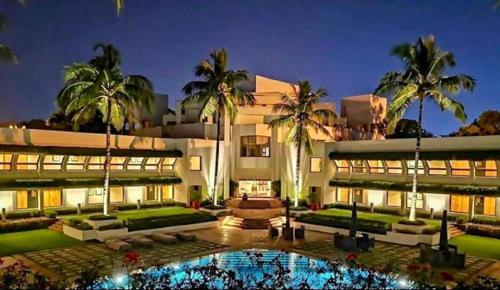 a large white building with palm trees and a pool at Trident Bhubaneswar in Bhubaneshwar
