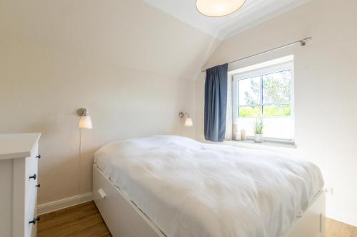 een witte slaapkamer met een bed en een raam bij An der Steilküste Wohnung 01 in Boltenhagen