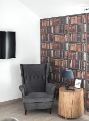 a chair and a table in a room with a wall of books at Wilczarz in Duszniki Zdrój
