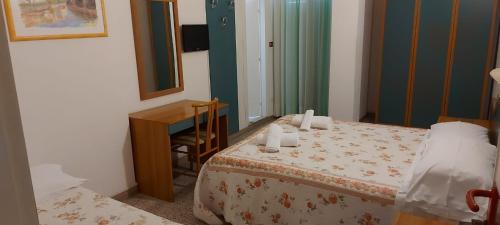 una camera con letto, scrivania e specchio di Hotel Santini a Rimini