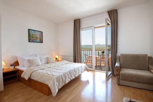 a bedroom with a bed and a chair and a balcony at Apartments Knežević in Neum