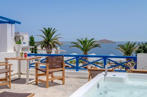 a patio area with a pool, chairs, and a balcony at Faros Resort in Azolimnos Syros