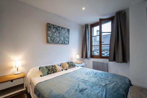 um quarto com uma cama com 2 candeeiros e uma janela em Le Puit Saint Jean 3 - Apartment for 2-4 people em Annecy