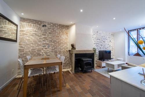 uma sala de estar com uma mesa e uma parede de tijolos em Le Puit Saint Jean 3 - Apartment for 2-4 people em Annecy