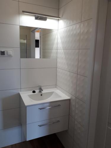 a white bathroom with a sink and a mirror at Domki Anusia Niechorze in Niechorze
