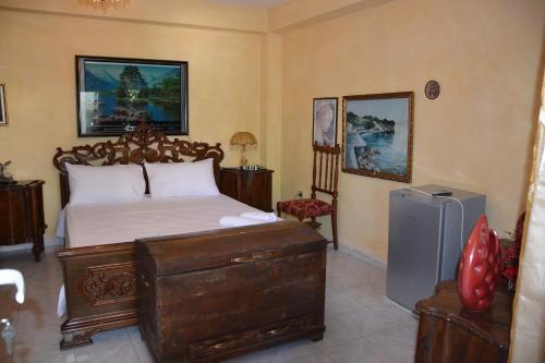 a bedroom with a wooden bed and a refrigerator at Lungomare private rooms in Vlorë