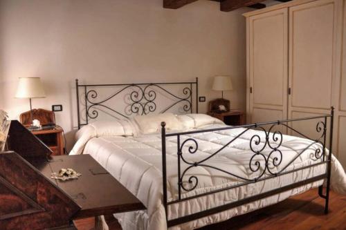 - une chambre avec un lit avec des draps blancs et une table dans l'établissement Santa Maria ad Valetudinarium, à Abbadia San Salvatore
