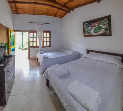 a bedroom with two twin beds and a kitchen at Finca Hotel Andaquies in Armenia