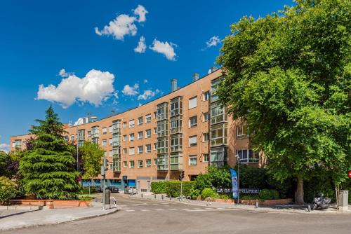 a large brick building with a tree in front of it at Las Huertas - Modern Accommodation in Madrid Conde Orgaz in Madrid