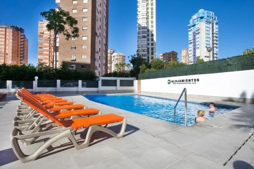 een zwembad met oranje ligstoelen en een zwembad bij Apartamentos Amalia By Mc in Benidorm