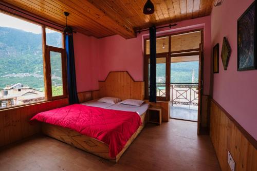 a bedroom with a bed in a room with windows at Voyageur Nest in Manāli