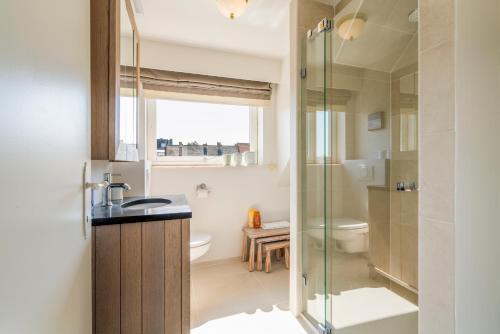 y baño con ducha, lavabo y aseo. en Spacious, warm and updated Home w parking & garden, en Bredene