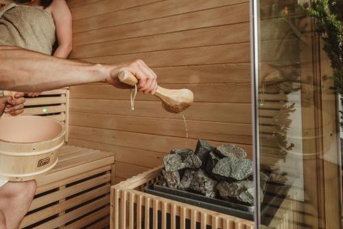 a person is pouring water from a brush into a sauna at Apartment Judith - Gallhof in Vollan