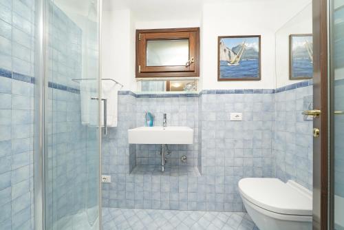 W wyłożonej niebieskimi kafelkami łazience znajduje się umywalka i toaleta. w obiekcie Villa Bouganville w mieście Toscolano Maderno