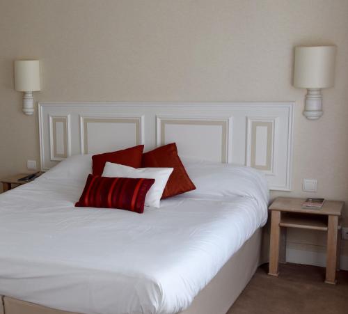 a white bed with two red pillows on it at The Originals City, Hôtel Chantecler, Le Mans in Le Mans