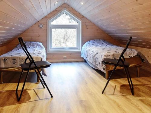 Un dormitorio abuhardillado con dos camas y una ventana. en 8 person holiday home in VATNE, en Vatne