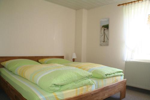 a bedroom with a bed with green sheets and a window at Wohnung-Krabbe in Süderende