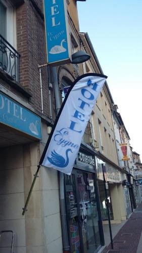 un panneau indiquant un magasin portant un drapeau sur un bâtiment dans l'établissement Hôtel le cygne, à Gournay-en-Bray