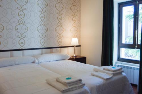 a bedroom with a white bed with towels on it at Casa del Cura in Las Navas del Marqués