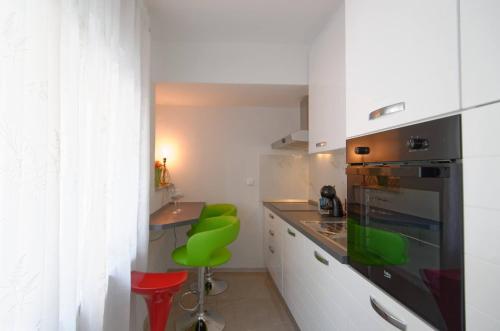 a kitchen with white cabinets and a green stool at Maximus in Čakovec