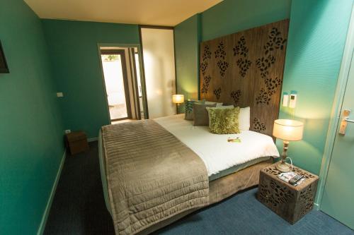 Grand-FougerayHÔTEL LES PALIS的一间卧室设有一张带绿色墙壁的大床