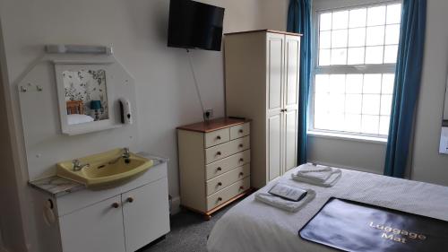 a small bedroom with a sink and a bed at Elnor Guest House in Liskeard