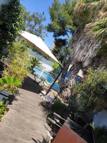 a patio with an umbrella and chairs and a table at VILLA privée MYRIAMI BEACH in Lattes