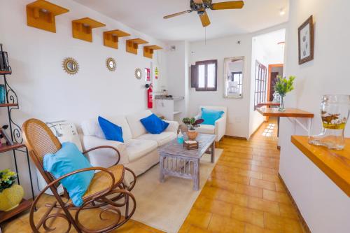 Pensión Sevillano في نيرخا: غرفة معيشة مع أريكة بيضاء ووسائد زرقاء