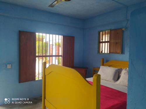 a bedroom with a yellow bed and two windows at Los Versos de Zaira in San Onofre