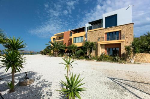 a building on the beach with palm trees in front at Pachia Ammos Falasarna in Falasarna