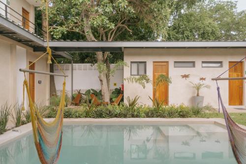 a house with a swimming pool and two hammocks at Hostik Hostal in Mérida