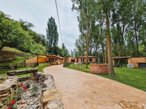 a stone driveway leading to a house with trees at El Molino de la Pastora in Valacloche