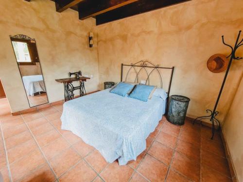 a bedroom with a bed with blue pillows on it at El Molino de la Pastora in Valacloche