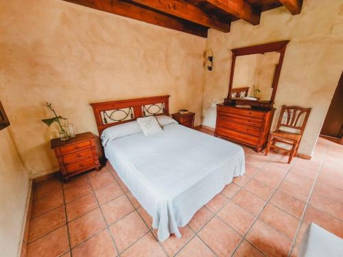 a bedroom with a bed and a dresser and a mirror at El Molino de la Pastora in Valacloche