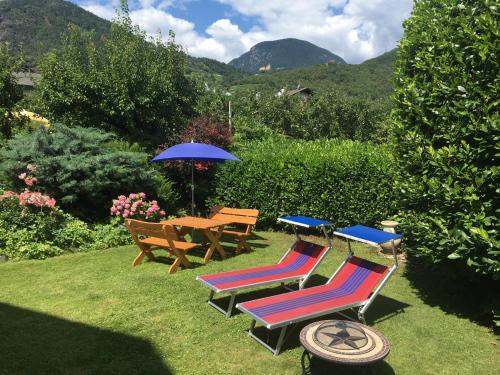 a group of chairs and a table with an umbrella at Garni Rebhof in Nalles