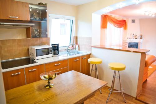 a kitchen with a wooden table and yellow stools at Vila Teo in Bărăşti