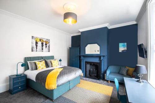 a bedroom with blue walls and a bed and a desk at BrickSage Rooms, King's Lynn South Gate in King's Lynn