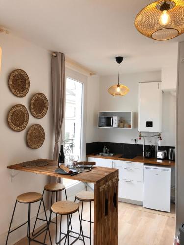 - une cuisine avec une table et des tabourets en bois dans l'établissement Le Tanin -Appartement entier avec Balcon, à Saumur