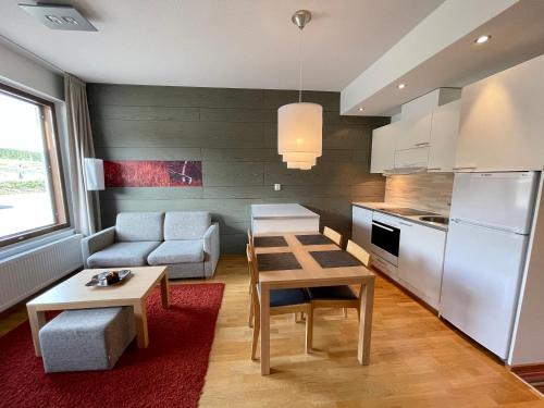 a kitchen and living room with a table and a couch at Salomon Chalet 7207 - Parivuoteellinen makuuhuone ja lisäksi makuualkovi - Täydellinen pariskunnille ja perheille in Ylläsjärvi