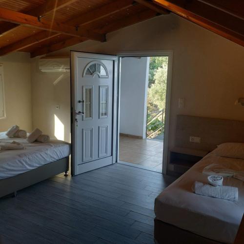 a room with two beds and a door leading to a patio at Karantola Studios Kallirachi in Skala Kallirachis