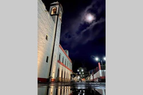 ein Gebäude mit einem Uhrturm in der Nacht auf einer Straße in der Unterkunft Posada Tres Marías Un rincón de Magia Zacateca. in Zacatlán