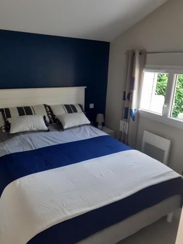 a blue and white bedroom with a large bed at Chalet tout équipé, terrasse in Gujan-Mestras