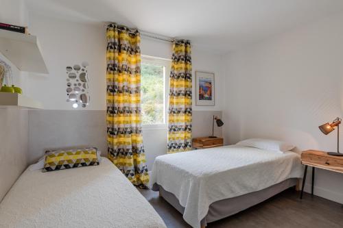 two beds in a bedroom with yellow curtains at STELLA MARE in Algajola