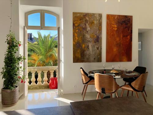 une salle à manger avec une table et des chaises et une fenêtre dans l'établissement Appartement à la Roquette, dans l'Hotel de Divonne, classé., à Arles