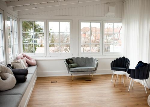 a living room with a couch and two chairs and windows at Mały Sopot Boutique in Iława